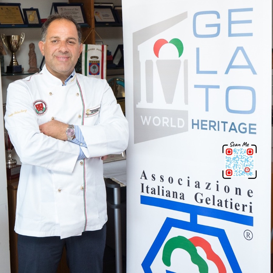 Maurizio Manzi, founder of Naturalis Gelato Italiano, in his chef jacket beside the Gelato World Heritage banner of the Italian Gelato Makers Association